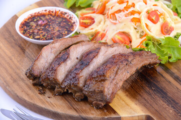 Roasted pork steak on the wooden plate with thai sauce.