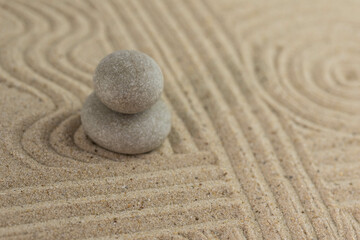 Fototapeta na wymiar Zen sand garden meditation stone background with copy space. Stones and lines drawing in sand for relaxation. Concept of harmony, balance and meditation, spa, massage, relax