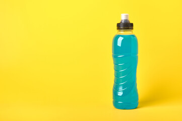 Isotonic energy blue transparent sport drink in plastic bottle on yellow background. Allows to maintain the most optimal balance of water, salt and electrolytes when playing sports