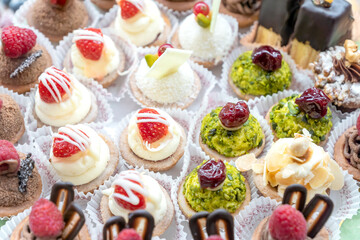 Pastry shop display window with variety of mini desserts and cakes, candy bar, selective focus.