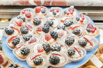 Pastry shop display window with variety of mini desserts and cakes, selective focus