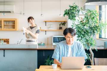 Obraz premium テレワークする男性とキッチンにいる女性（笑顔） 