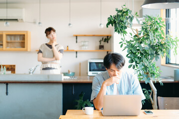 家事をしながら男性を疑う女性（夫婦喧嘩）
