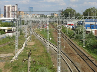 suburban railway tracks with poles and rails in summer