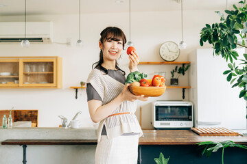 キッチンの前に野菜を持つ女性（トマト）
