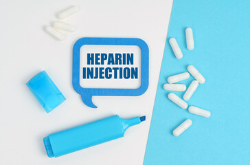 On a white and blue table are pills, a marker and a blue plaque with the inscription - Heparin Injection