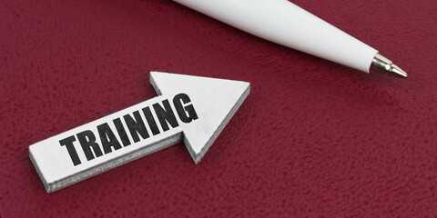 On a red background lies a white pen and a white arrow with the inscription - TRAINING