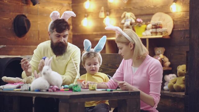 Easter family of mother, father and child son painted eggs, wearing bunny ears. Family Celebrating Easter with kids at home, Funny easter bunny rabbits parents. Spring family holidays.
