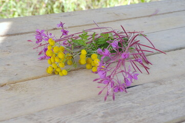 bouquet of narrow-leaved fireweed or Ivan-tea and tansy on a wooden table. Macro shooting, the background is blurred