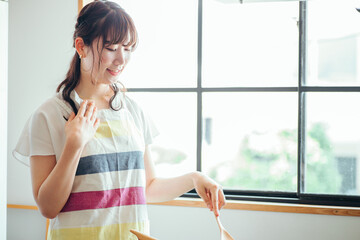 キッチンでフライパンを使う女性（疲れる）
