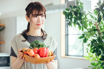 キッチンの前に野菜を持つ女性
