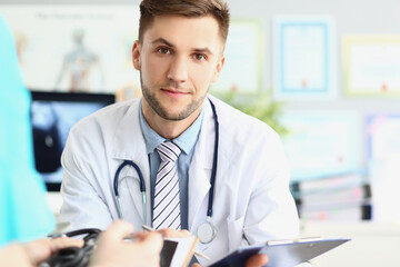 Fototapeta premium Attractive young medical worker in white uniform, wait patient for planned appointment