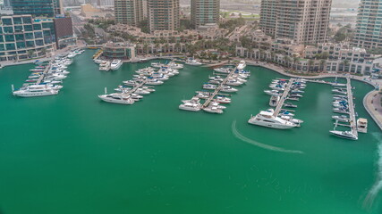 Luxury boats and yachts docked in Dubai Marina aerial all day timelapse.