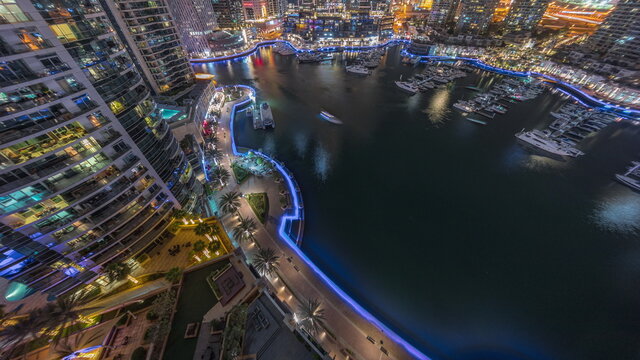 Waterfront promenade with palms in Dubai Marina aerial night timelapse. © neiezhmakov