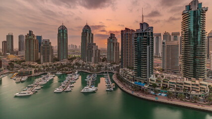 Obraz premium Sunrise over Dubai Marina luxury tourist district with skyscrapers and towers around canal aerial timelapse
