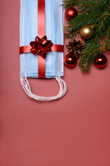 medical protective masks covid-19 are blue on a red background. medical masks a gift for Christmas and new year with xmas decor a fir branch and balls for the holiday
