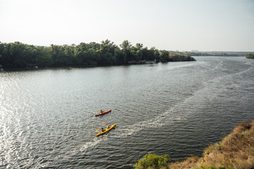 Fototapeta premium Two women and one man kayaking in the river at summer morning. Back view