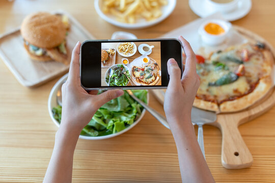 italian food. The restaurant owner takes a picture of the food on the table with a smartphone to post on a website. Online food delivery and ordering service