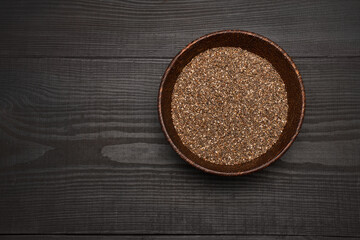 Organic natural chia seeds in wooden bowl close-up on dark wooden background or table