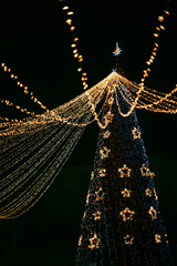 Long exposure night shot of a uniquely decorated main Christmas tree in the square after rain with reflection.