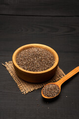 Organic natural chia seeds in wooden bowl close-up on dark wooden background or table
