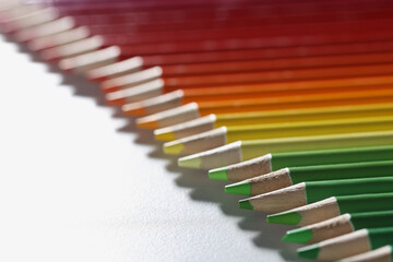 Colourful pencils set perfectly arranged in line on white surface
