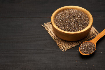Organic natural chia seeds in wooden bowl close-up on dark wooden background or table