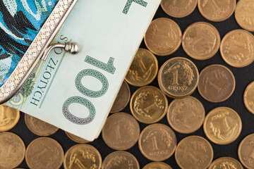 Scattered one grosz  coins on a black table and a blue-black purse lying next to it, with a 100 zloty bill sticking out of it. - obrazy, fototapety, plakaty