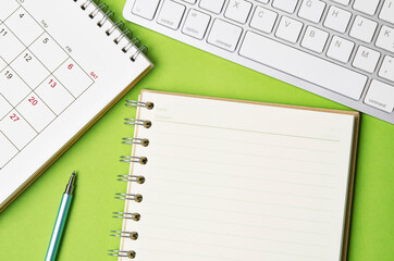 Open blank diary and desk calendar with computer keyboard.