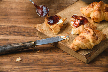 Croissants with honey on a wooden table.