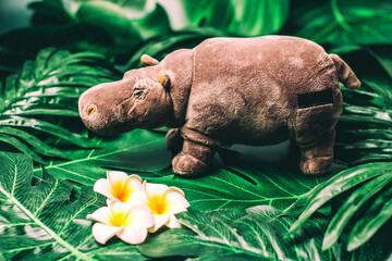 toy hippo on green leaves and flowers