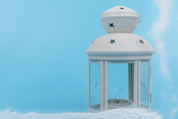 White lantern with candle inside on blue background. Christmas decoration. Copy space.