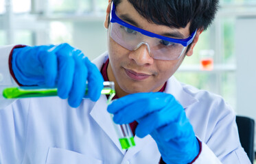 Closeup shot hands of Asian male scientist in white lab coat safety goggles and rubber gloves in...