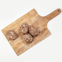 Raw burgers cutlets from organic beef meat on wooden cutting board isolated on white