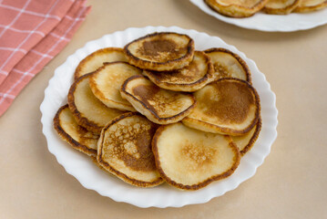 Obraz na płótnie Canvas Heap of fried pancakes in white plate on beige background