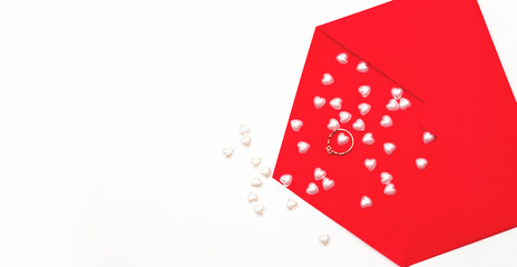 Marry me concept, wedding engagement ring with with red paper envelope and hearts on white background. Happy valentines day present. Close up, copy space, top view