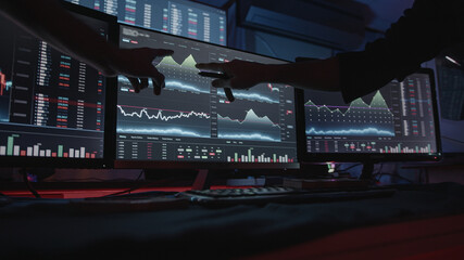 Two professional male economists looking at stock charts on monitors doing AltCoin analysis