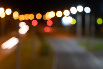 Fototapeta premium blurred lights of the night city with a view of the roadway. multicolored lights of city lanterns in out of focus. bright abstract background on the desktop