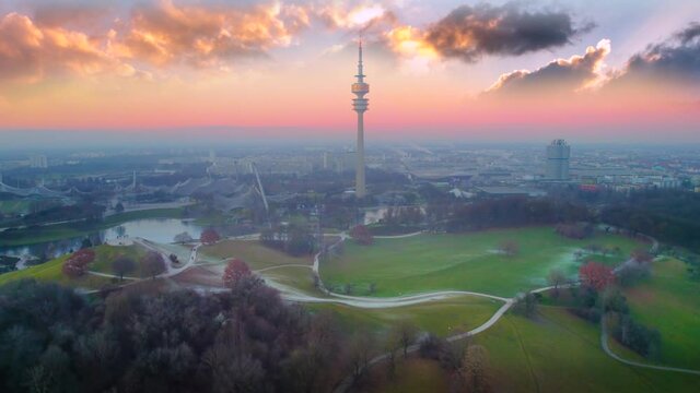 Munich aerial drone video tv tower skyline view at sunset colored sky olympoa park view from above germany.