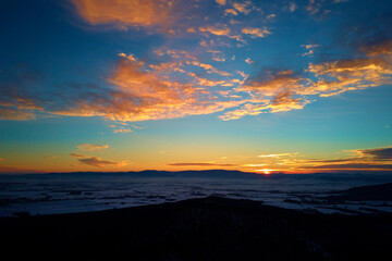 Sunset over mountans covered with forest, beautiful winter landscape, nature background, aerial view