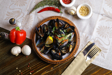 Served with mussels with greens of a slice of lemon, cutlery, whole sweet red peppers, hot red peppers, white mushrooms, a branch of rosemary.