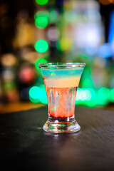 In the glass, the cocktail is brown-red, the top is white and the top is emerald, which is set on fire, the layers are not mixed.