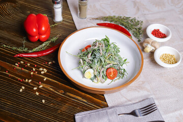 On a dark countertop, a light linen napkin, on a cutting board Served salad with rucola leaves, boiled tongue cut into long slices with sauce A couple of salt and pepper, cutlery, red peppers decorate