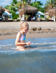 Little girl playing on the beach by the sea