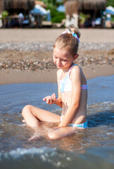 Little girl playing on the beach by the sea