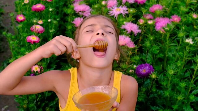 The child eats honey in the garden. Selective focus.