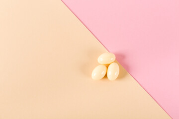 Three tablets over pink and beige background. Vaginal antibacterial capsules. Close-up. Blister pack was started. Copy space. Medical treatment. Flat lay. Mockup design. Nobody. Template. Medicine