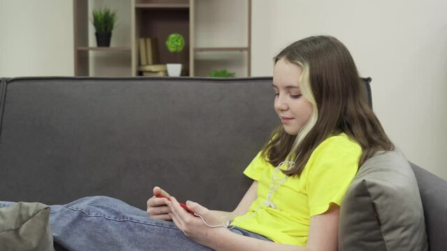 Happy teenage girl wearing headphones watching a video on her smartphone