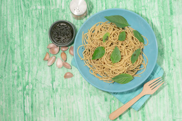 Pasta with pesto sauce in plate on green background Italian food.