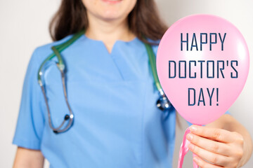 A doctor in a blue uniform holds a blue balloon with the text Happy Doctor's Day